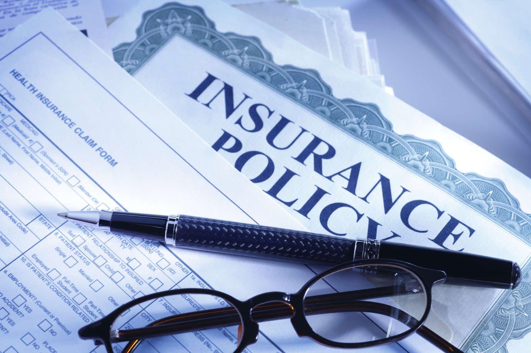 Illustrative photograph of insurance documents with glasses and a pen