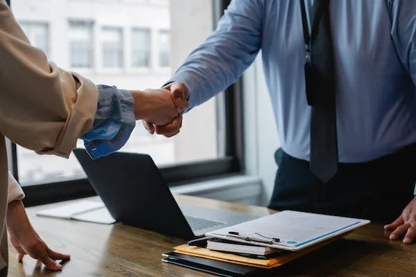 Business partners shaking hands over a desk